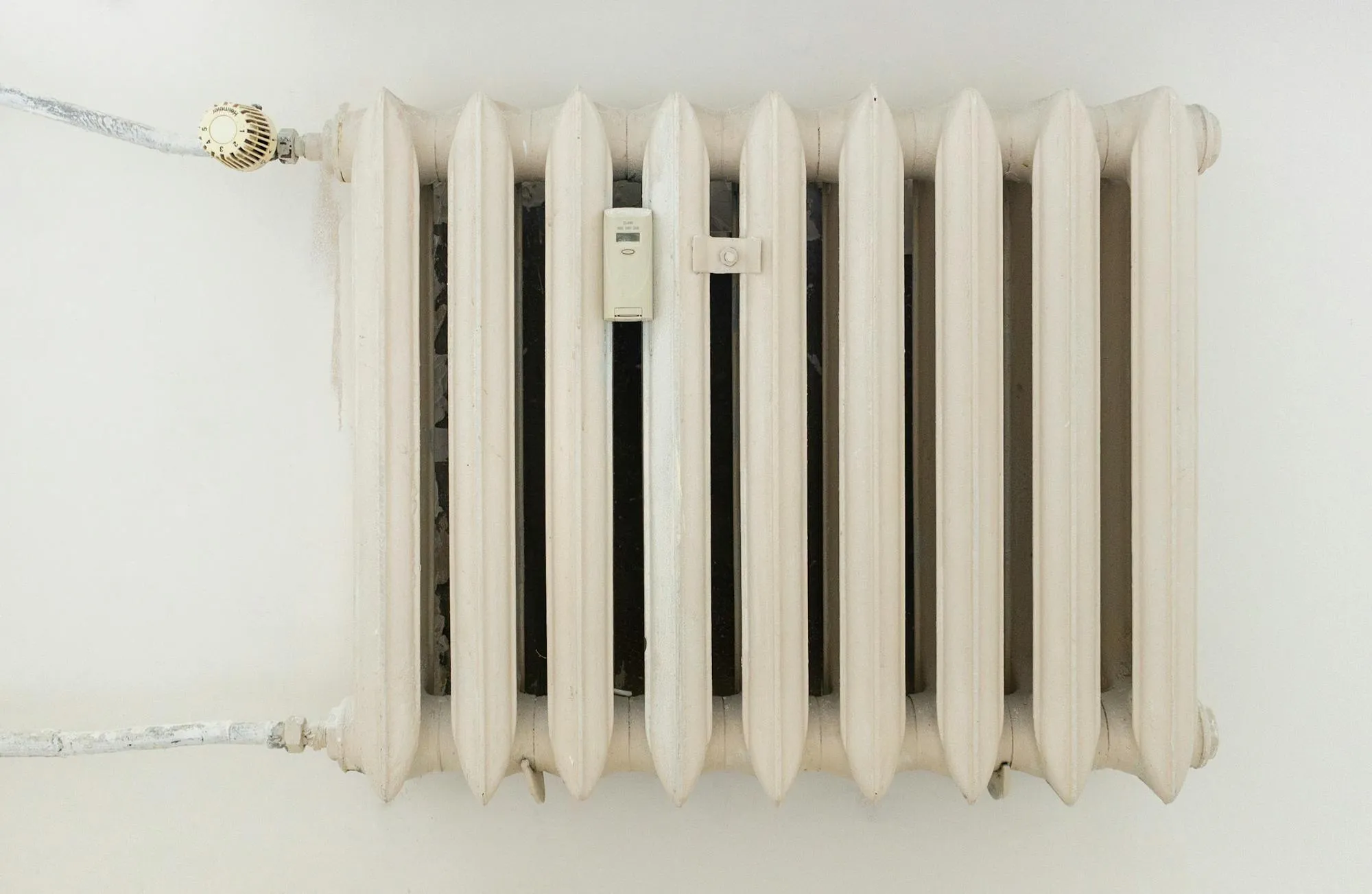 Cast-iron column radiator in a period property, fitted with a brass thermostatic valve.