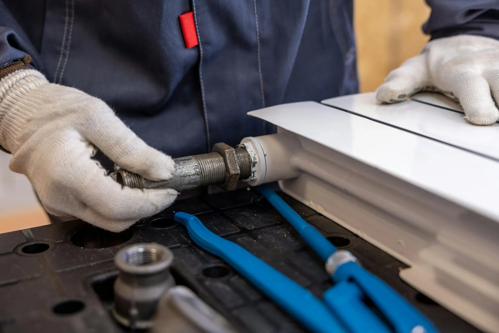 Plumber tightening a radiator union with adjustable pipe wrenches before fitting.